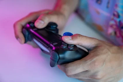 Manos de un jugador con controlador frente a pantalla de videojuego de ciencia ficción