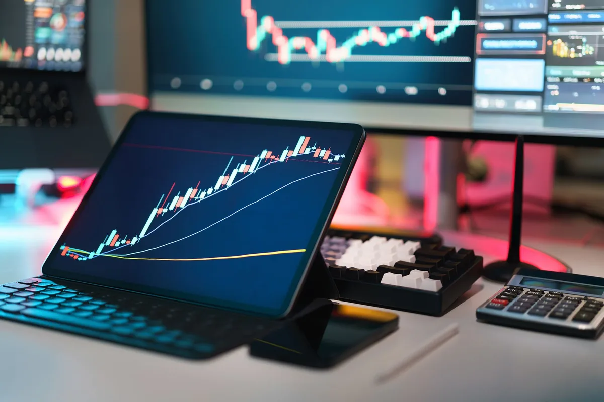 Móvil sobre escritorio con gráficos de precios al alza y componentes de memoria
