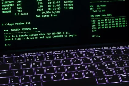 Mano escribiendo código en terminal Linux con interfaz Windows visible en el monitor de un desarrollador