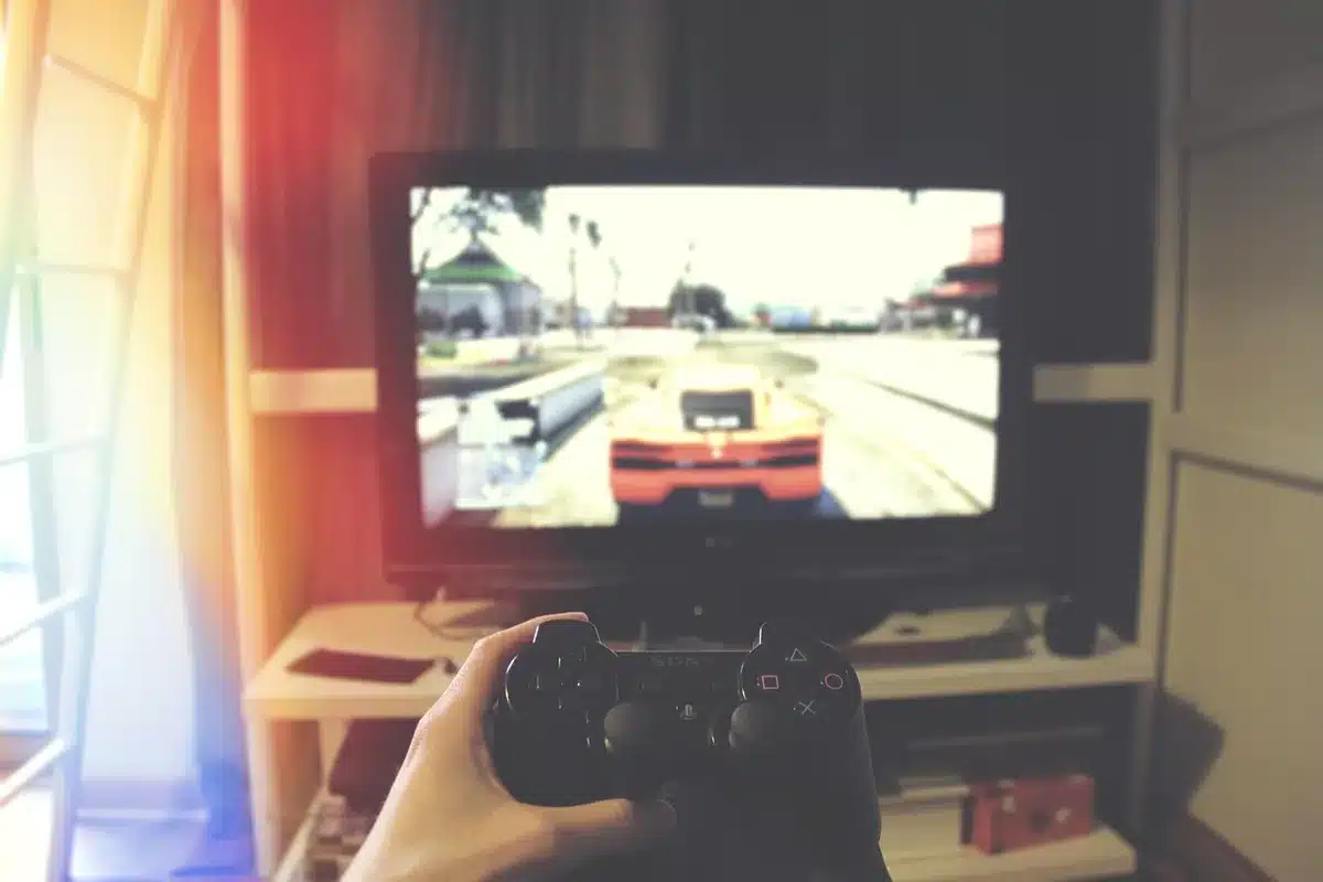 Mano sosteniendo un controlador de PlayStation en frente de una pantalla