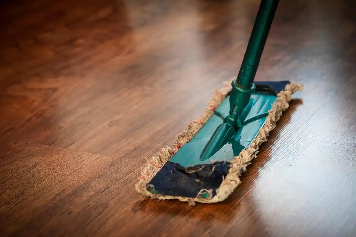 Close-up scene of anonymous hands placing a small microfiber mop cloth on an unbranded robot vacuum base on tile floor, no logos visible