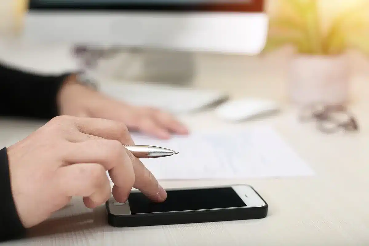 An anonymous pair of hands tapping a generic phone screen showing a simplified gallery layout, one image selected, background out of focus