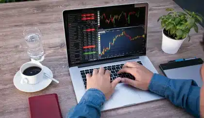 Manos anónimas usando un portátil en una mesa de trabajo con una taza de café