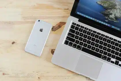 Manos escribiendo en un teclado de portátil con iconos de notificación flotantes en la pantalla