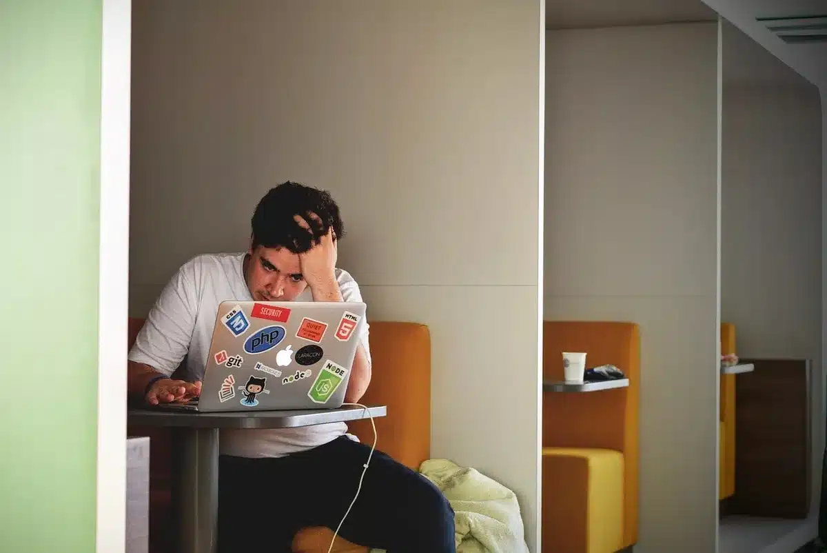 Empty caf&eacute; table with a laptop open showing a generic browser window, blurred people in background