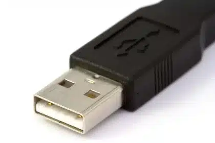 Manos conectando cables USB y un disco externo en un escritorio