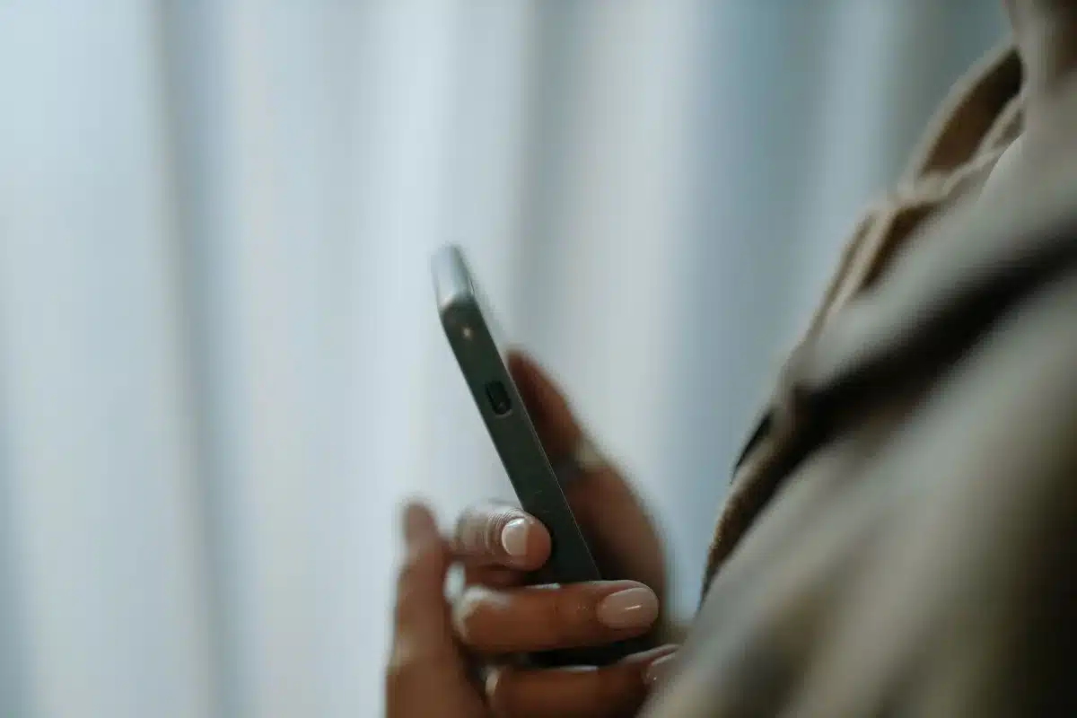 Anonymous hands holding an unbranded smartphone displaying camera UI icons, background blurred store shelves; no logos visible