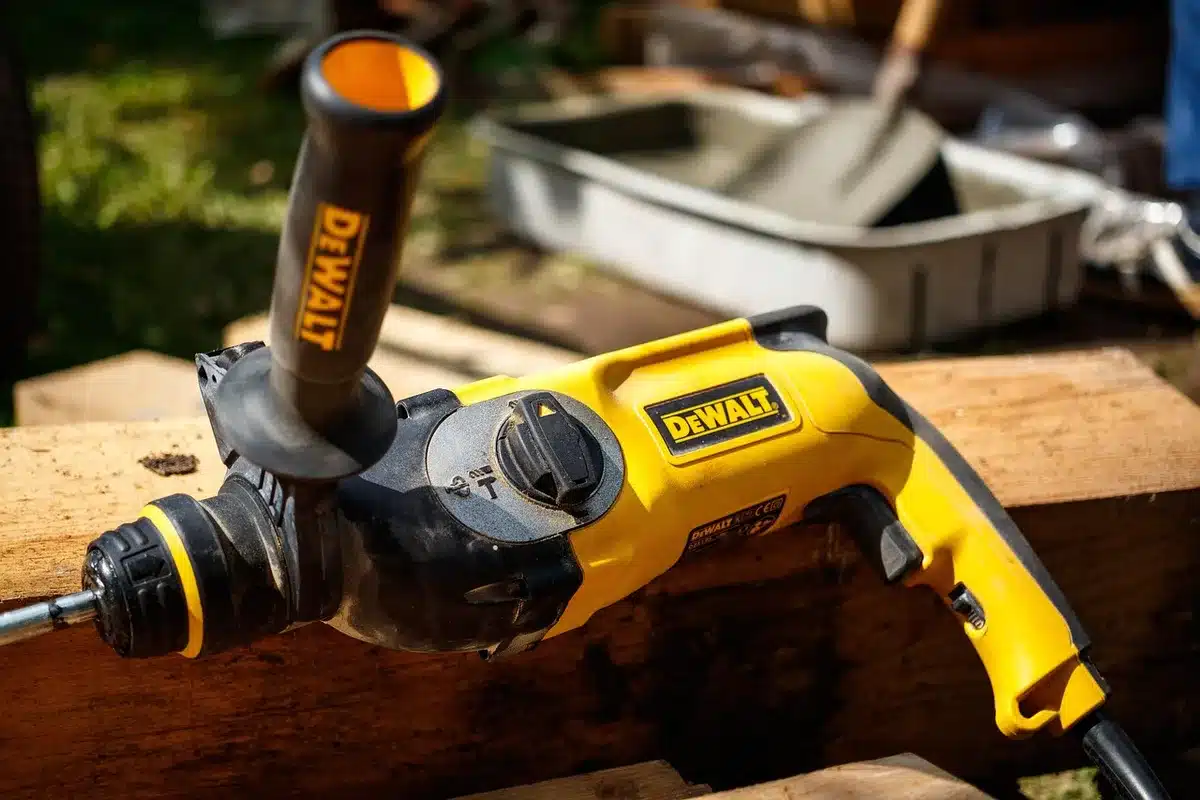 An empty aluminium tool case open on a workbench showing an unbranded cordless drill and scattered drill bits, soft workshop lighting