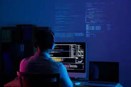 Manos sobre teclado frente a un portátil con ventanas de interfaz desenfocadas