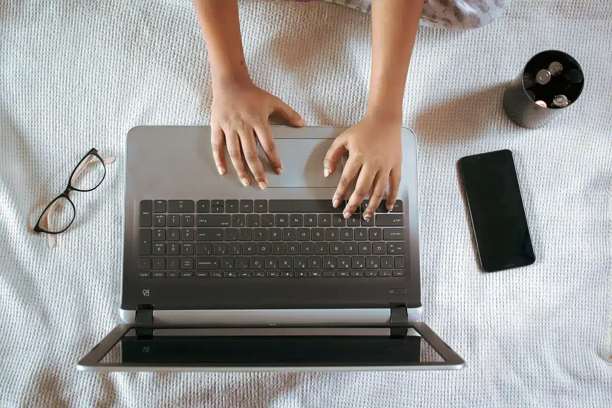 Mano junto a un portátil en un escritorio oscuro al atardecer, ajustando configuración