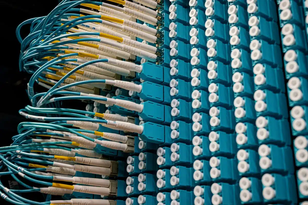 An anonymous server-rack corridor with a single technician silhouette in the distance, ambient maintenance lights and one removed drive tray on a cart &mdash; no logos or identifiable gear