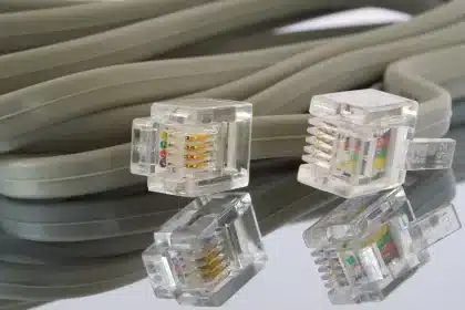 Manos anónimas junto a un portátil y un cable de red sobre una mesa