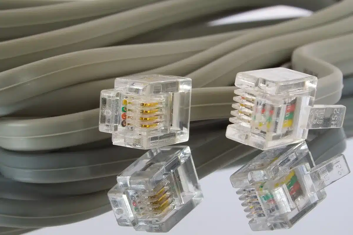Manos anónimas junto a un portátil y un cable de red sobre una mesa