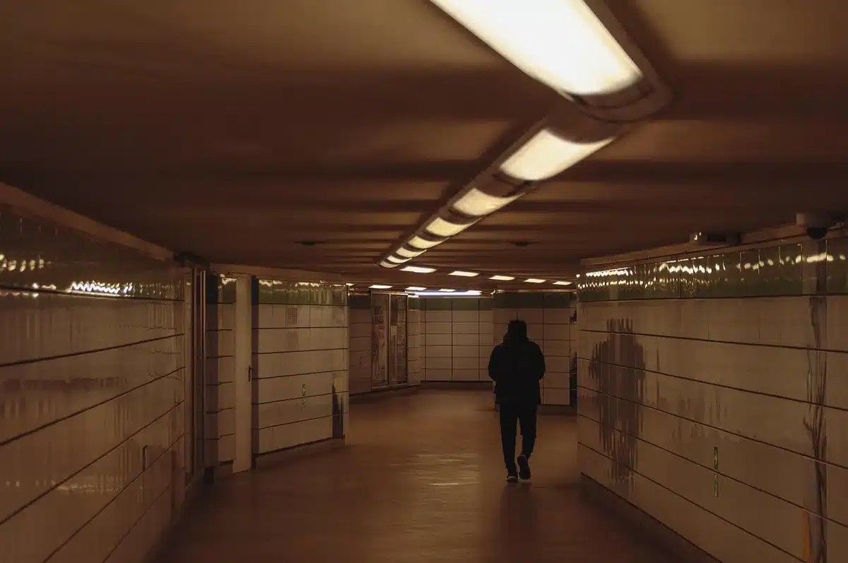 Túnel de metro semiinundado con mochila y rifle apoyados, ambiente postapocalíptico