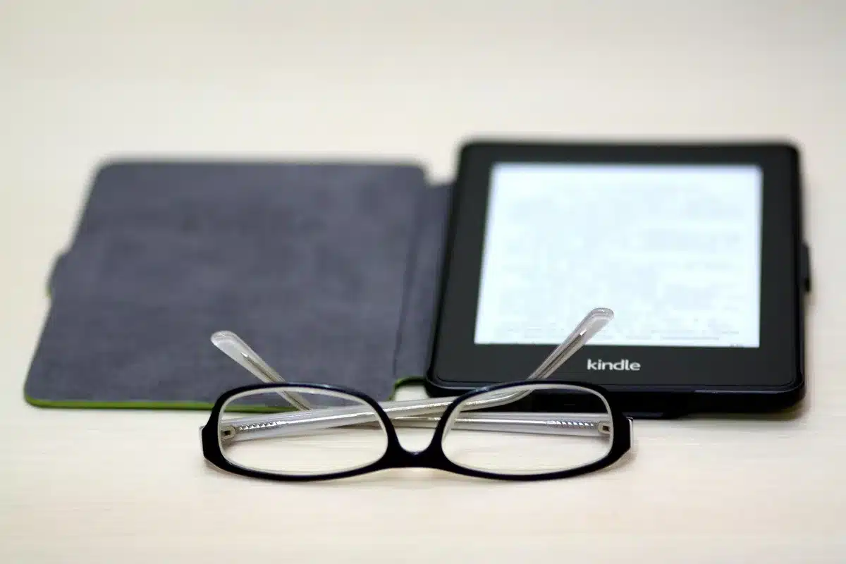 Empty retail shelf with multiple unbranded e-readers and a small smart speaker nearby, soft store lighting