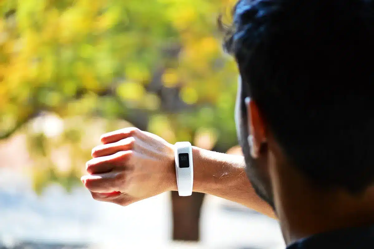 Close-up of an anonymous wrist wearing an unbranded smartwatch showing generic fitness screen, indoor lighting
