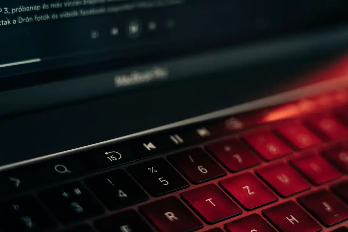 Close-up of a keyboard area and large OLED screen edge, showing slim bezels and an anonymous work desk in background