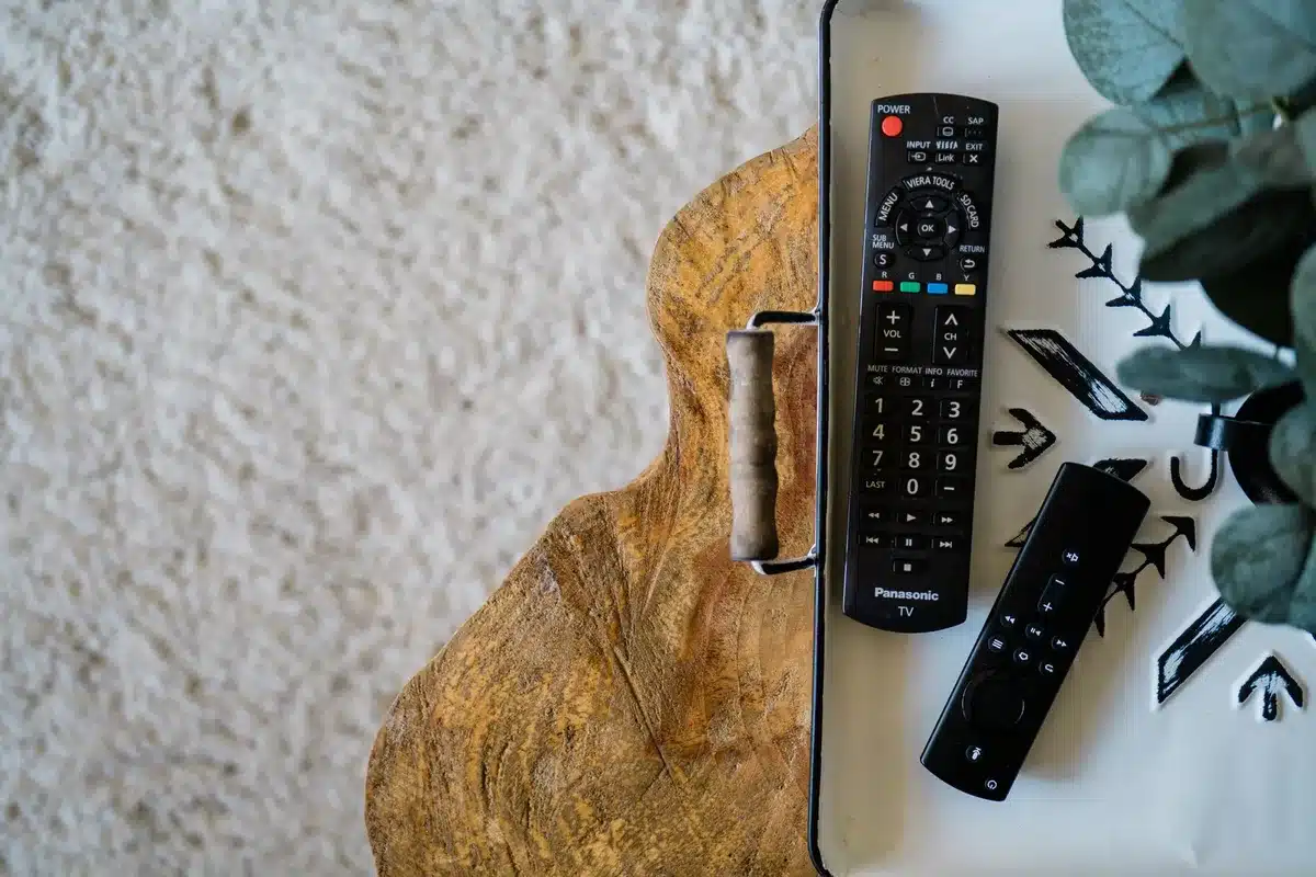Close-up of an anonymous hand holding a neutral remote control pointed at an unbranded cooling unit, background a living room setting