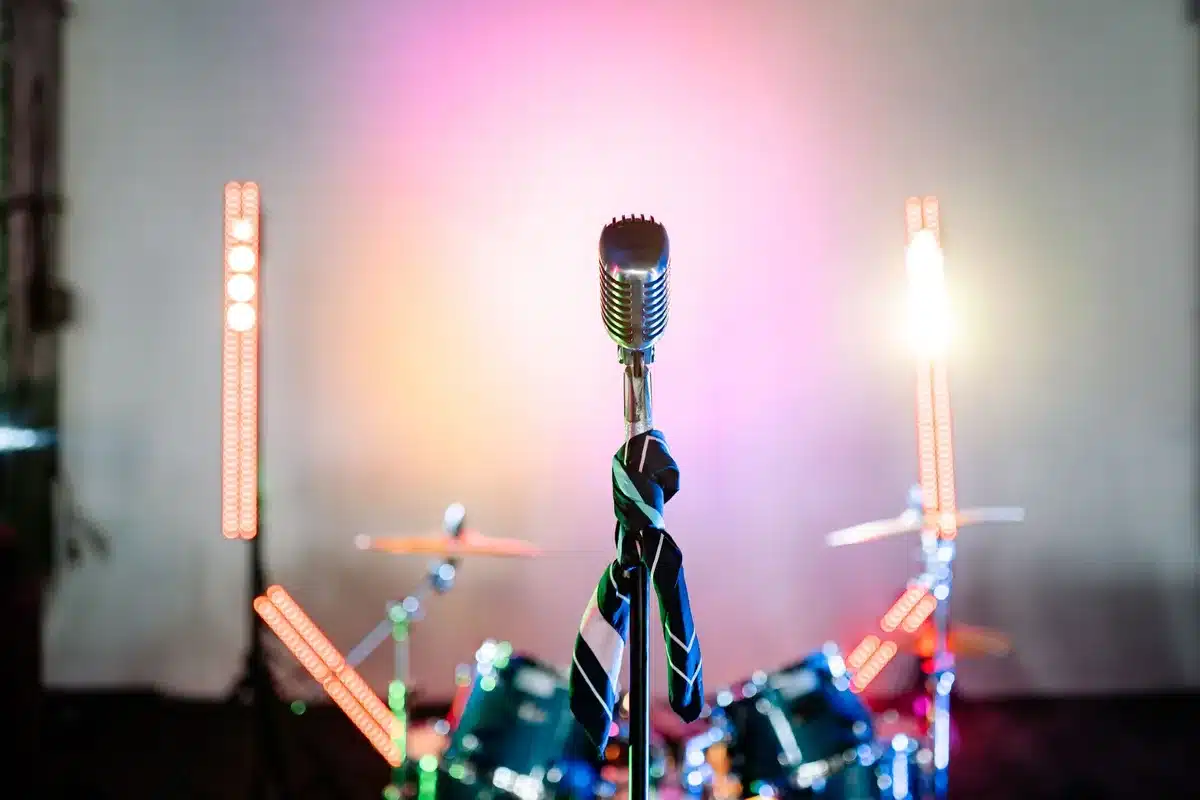 Close-up of a single vintage microphone on a studio table, a folded script beside it, empty and still, suggesting behind-the-scenes preparation.