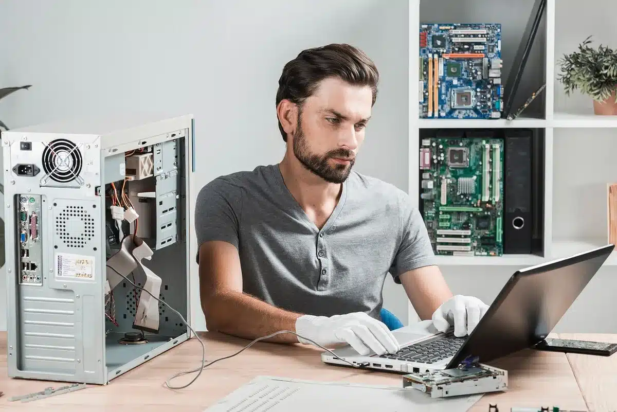 hands holding a small screwdriver near a laptop hinge on a workbench, no identifiable logos or people