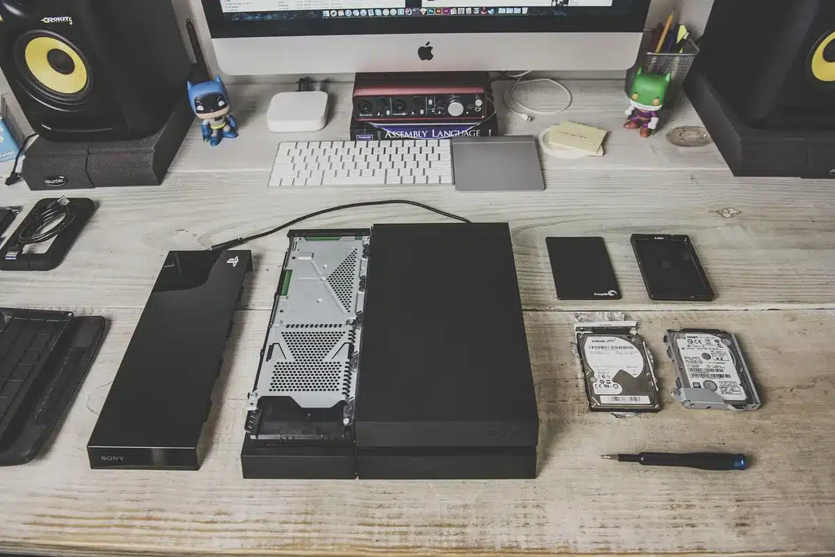 Close view of an external USB DVD‑RW drive connected to a modern laptop on a desk, disc tray slightly open and a generic game CD nearby