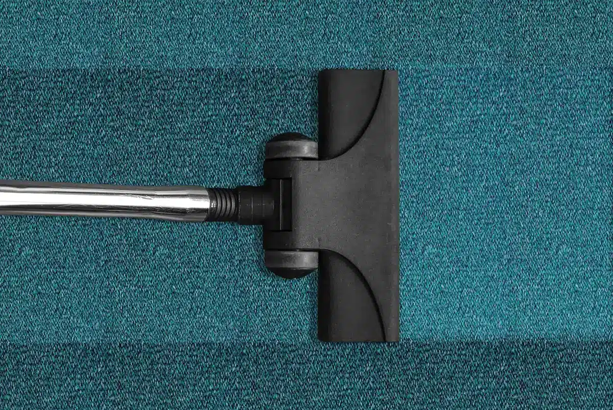 empty podium with a single modern cordless vacuum on top, confetti on the floor, blurred anonymous crowd in background