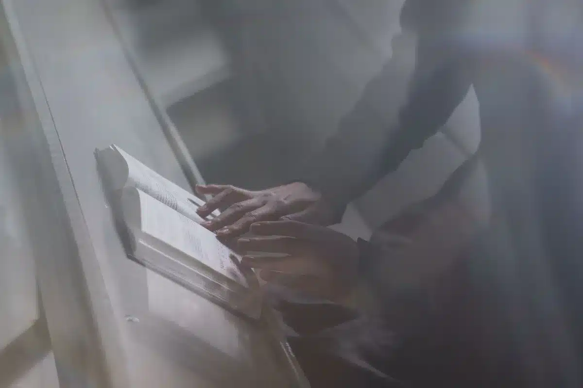 An anonymous person holding an unbranded e-reader from behind, screen showing a colored illustration, background blurred indoor setting
