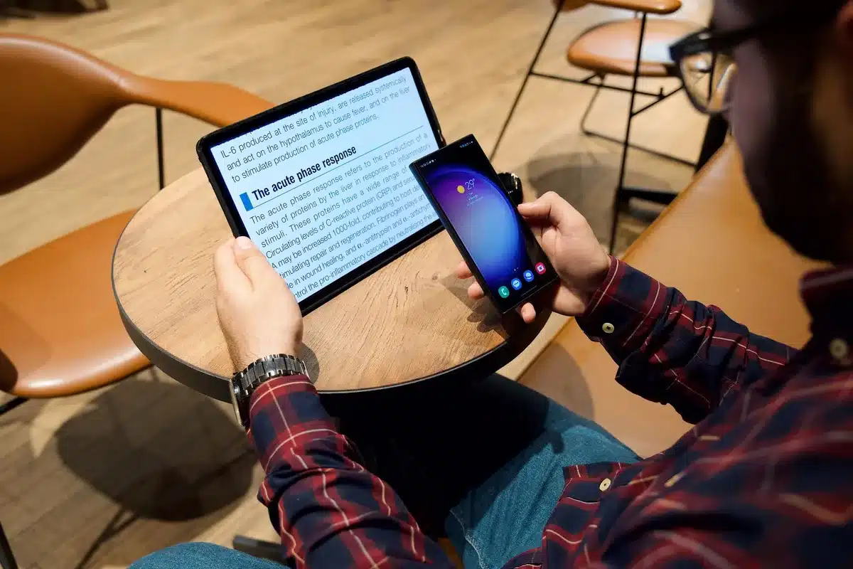 A folded smartphone-like device opened on a tabletop, screen showing two misaligned app windows and reflections on the hinge