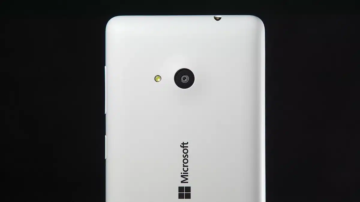 Close-up of an anonymous hand holding an unbranded smartphone showing a camera app interface, blurred background, no logos visible
