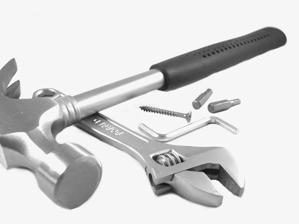 Anonymous hands holding a corded hammer drill above a workbench with scattered masonry dust and bits nearby