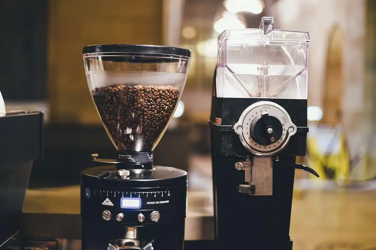 Empty kitchen counter with an unbranded modern stainless-steel coffee machine, a small bag of whole coffee beans and a ceramic cup, soft morning light