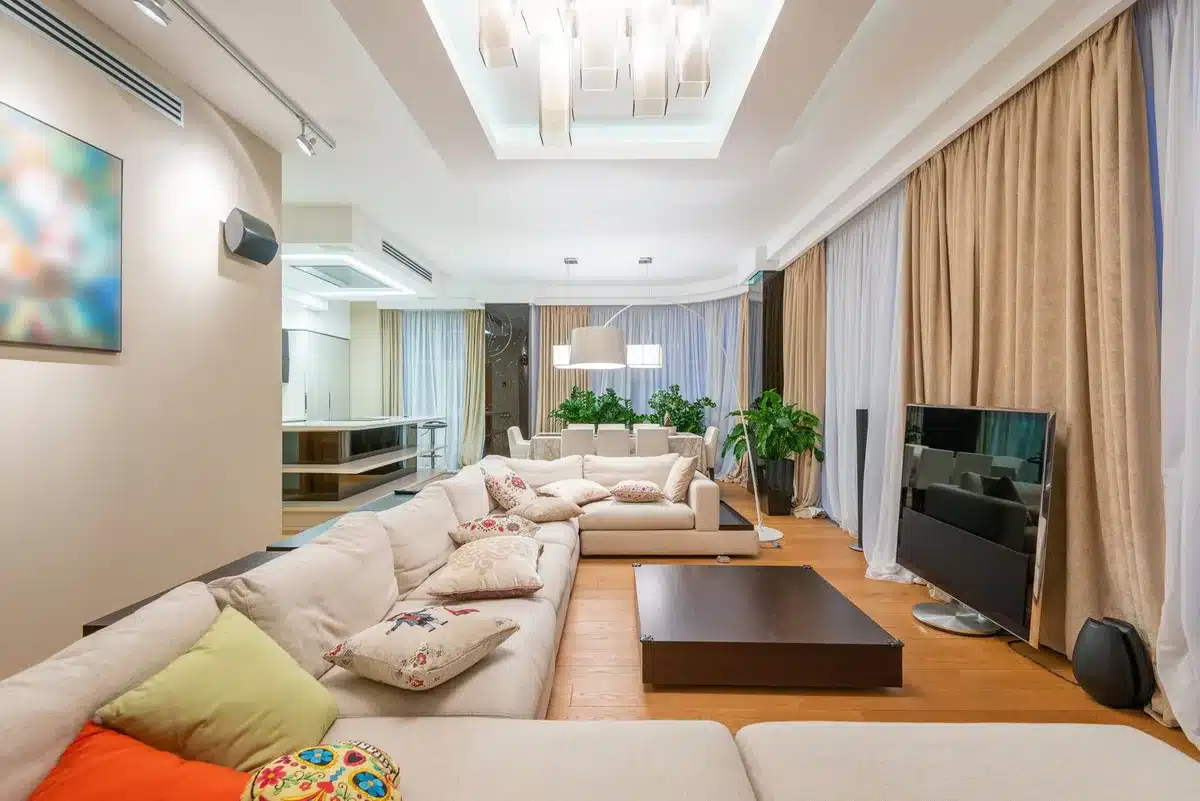 empty living room with a large unbranded 65-inch TV turned on, warm interior lighting, minimalist sofa and coffee table, no people