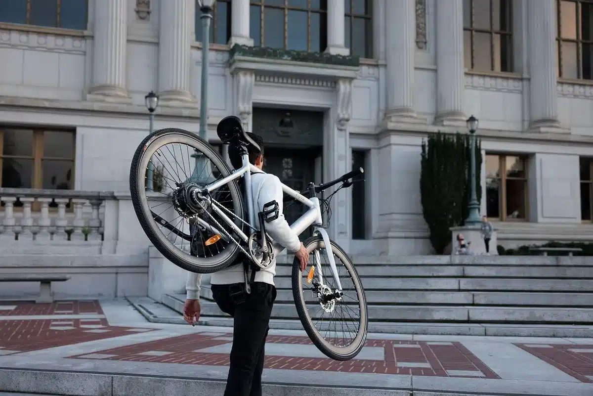 Folded unbranded city e-bike leaning against a plain wall, battery pack visible, no logos