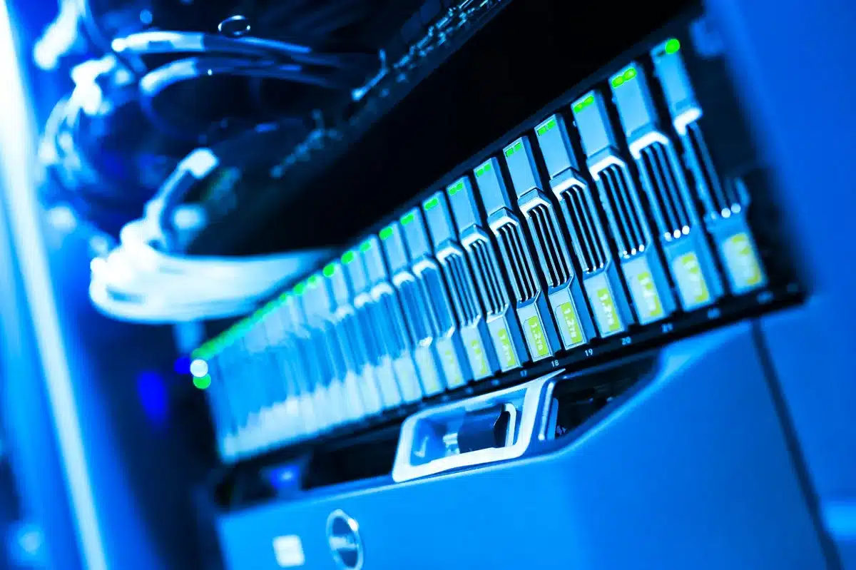 A dimly lit System32-style server rack with anonymous blurred cables and a single unbranded drive bay lit, evoking legacy systems