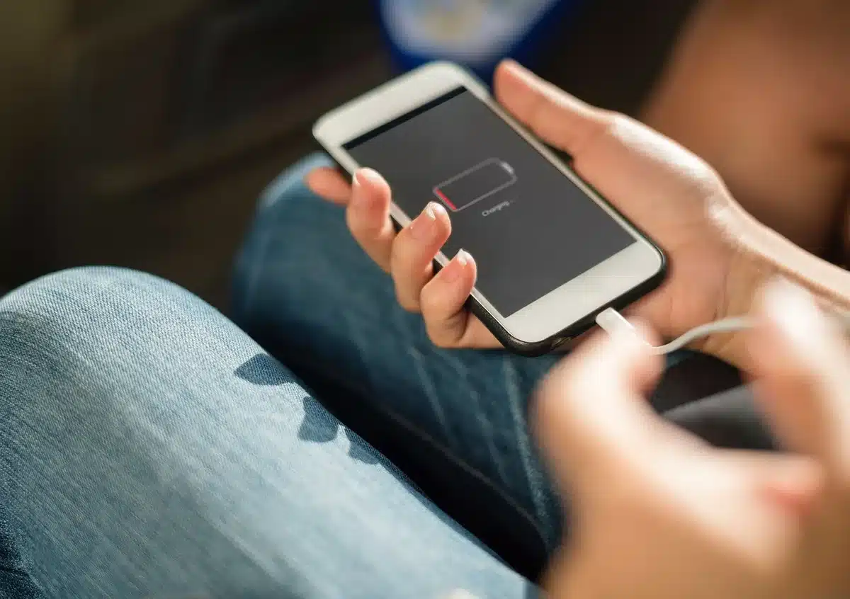 Close-up of an anonymous hand plugging a USB-C 45W charger into an unbranded phone on a plain table, transparent protective case nearby