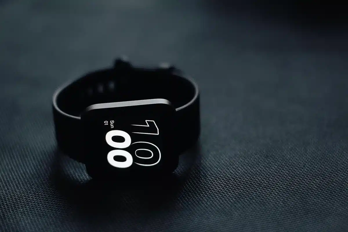 An anonymous wrist wearing a slim smartwatch, wrist turned away from camera showing watch profile and strap, indoor desk setting