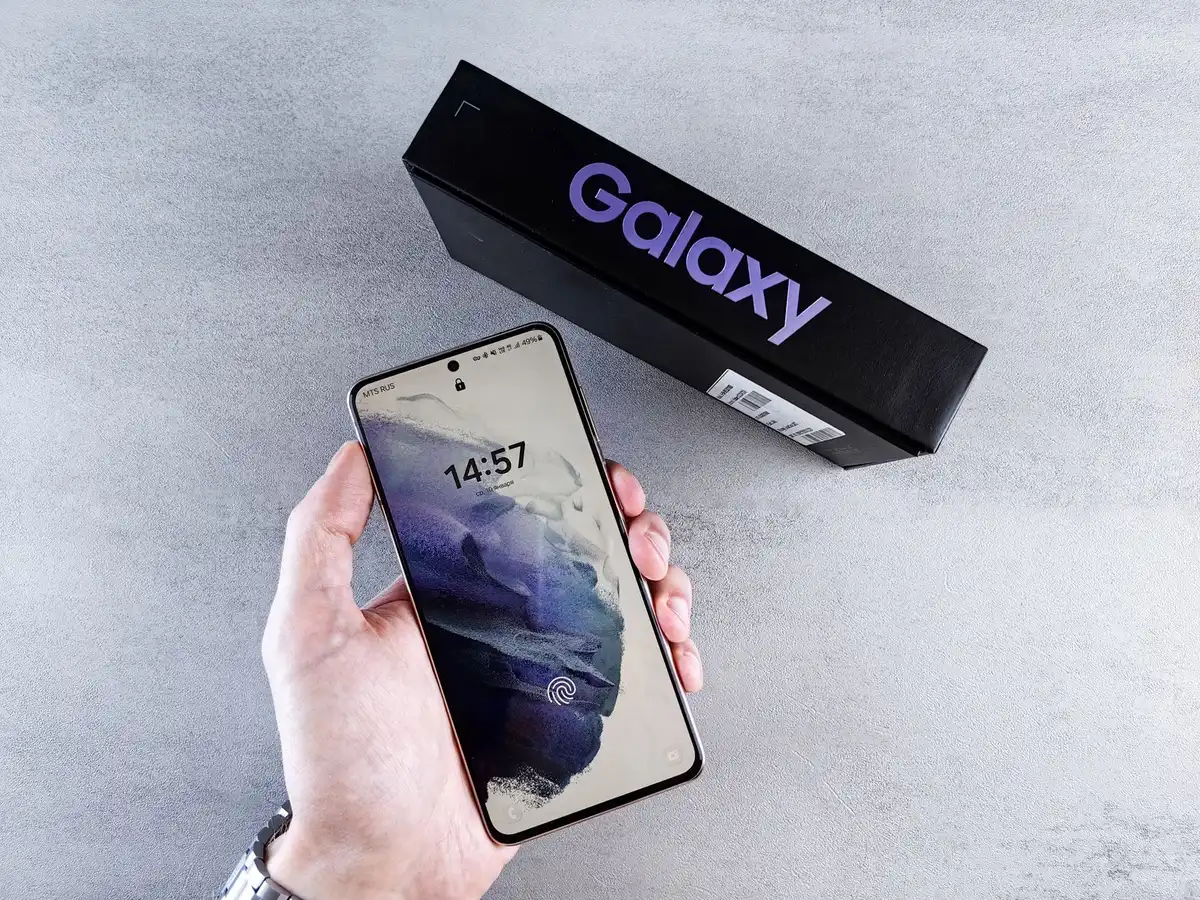 Close-up of an anonymous hand holding a generic unbranded smartphone box over a checkout counter, barcode out of focus