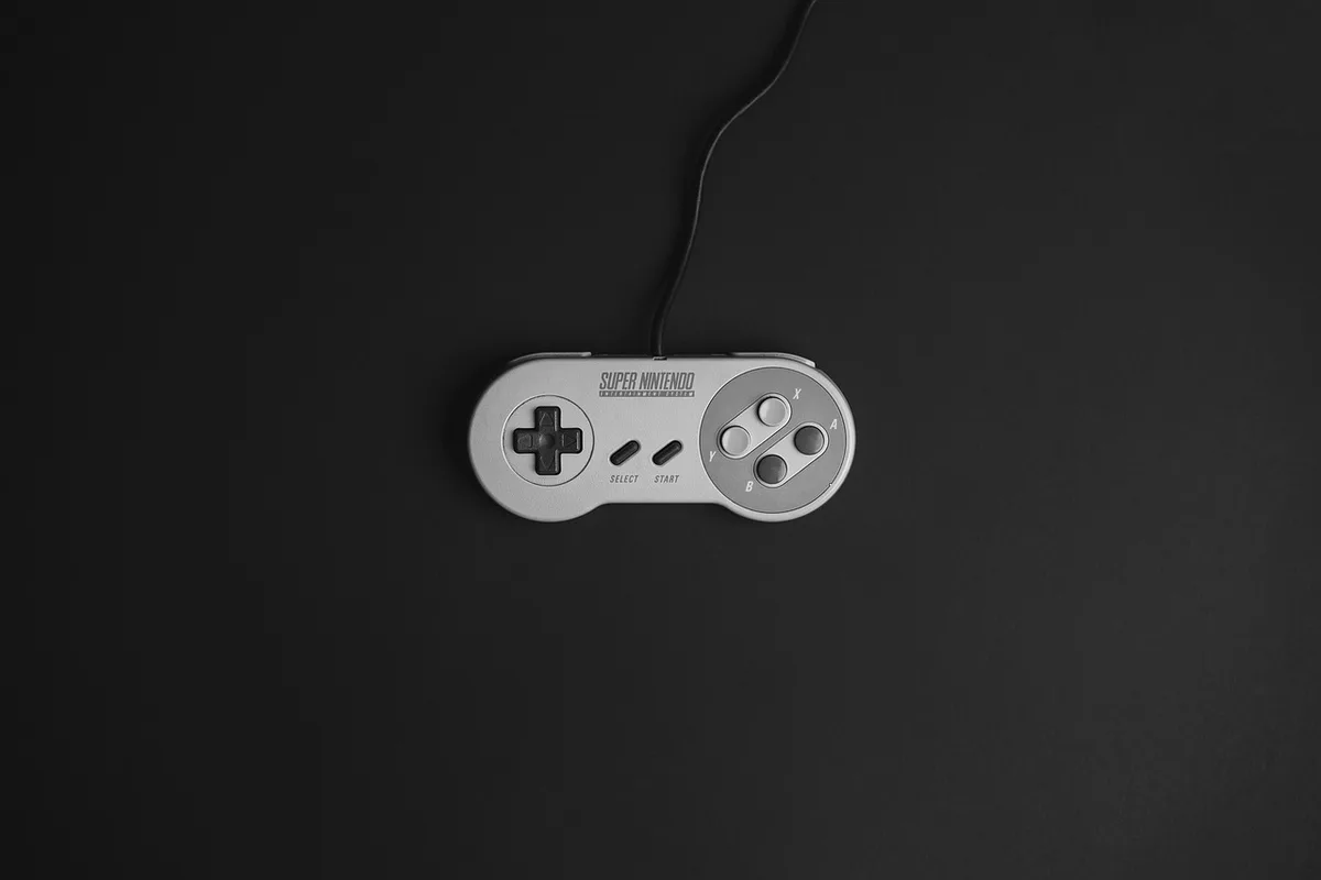 Manos sosteniendo mando frente a pantalla con lista de juegos