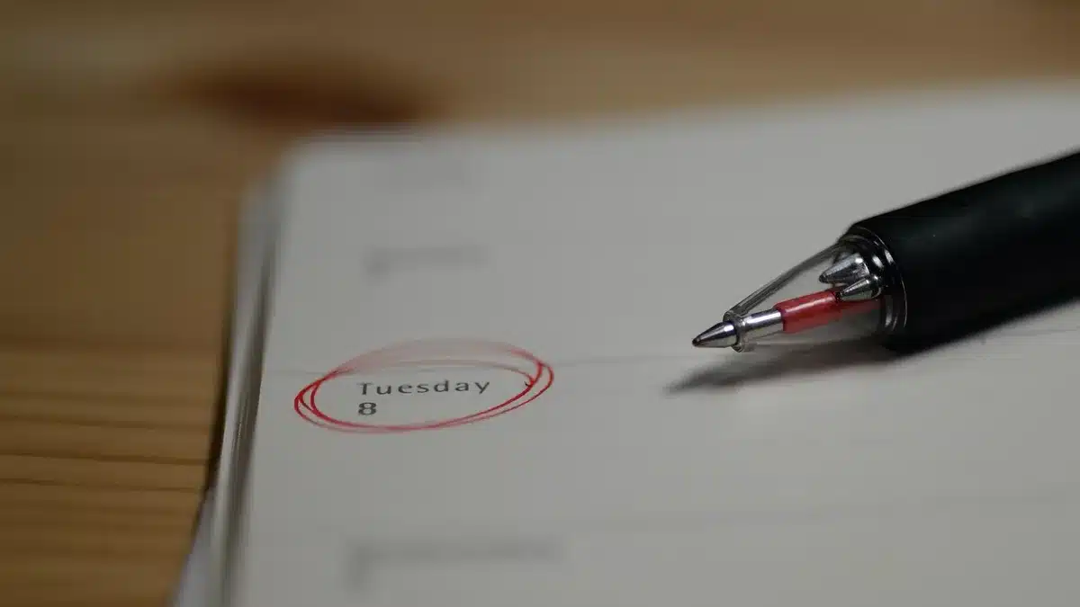 Calendario con fecha marcada y reloj sobre una mesa indicando día del anuncio