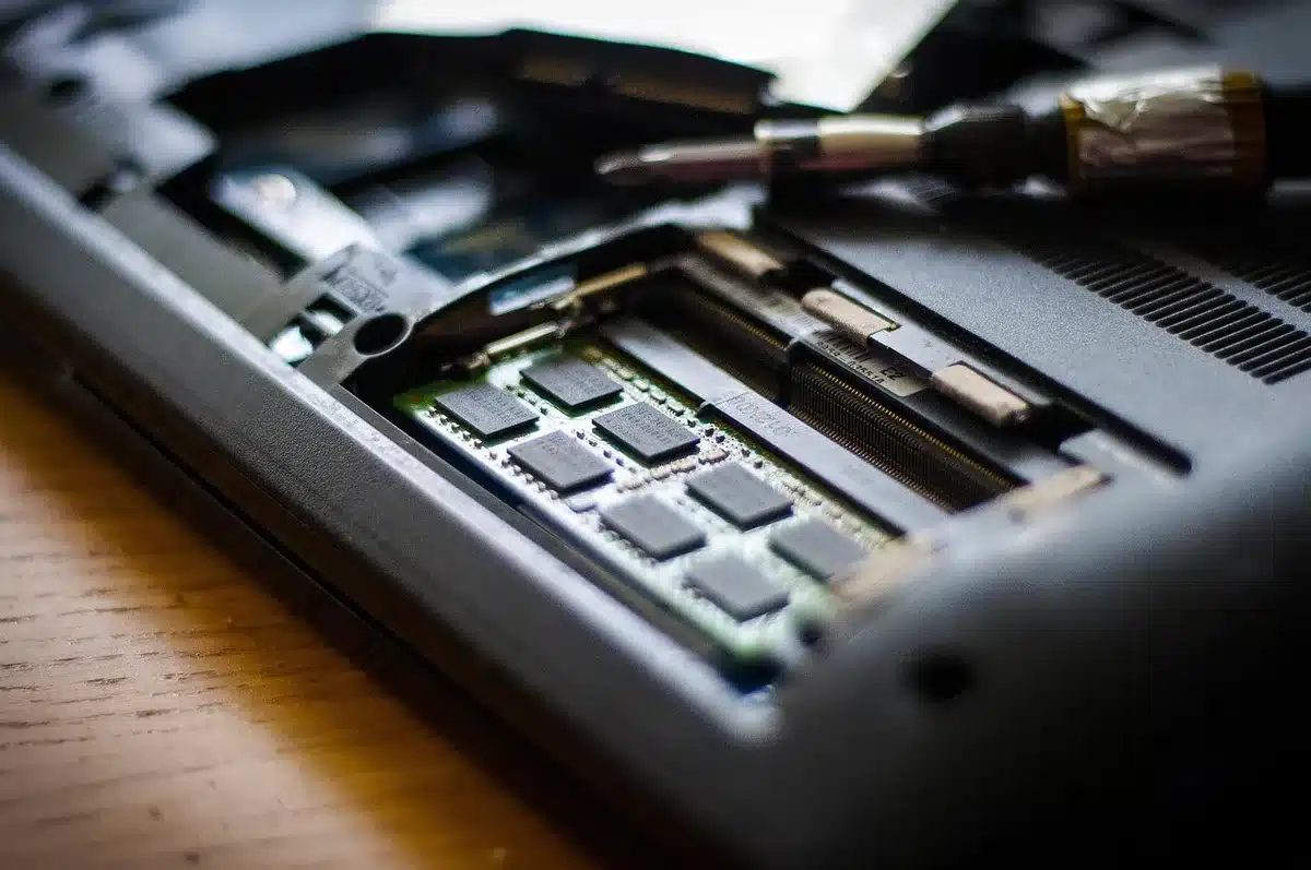 An anonymous, dimly lit workbench with an unbranded desktop motherboard and an unbranded graphics card placed side by side, a screwdriver and thermal paste nearby suggesting a PC build in progress