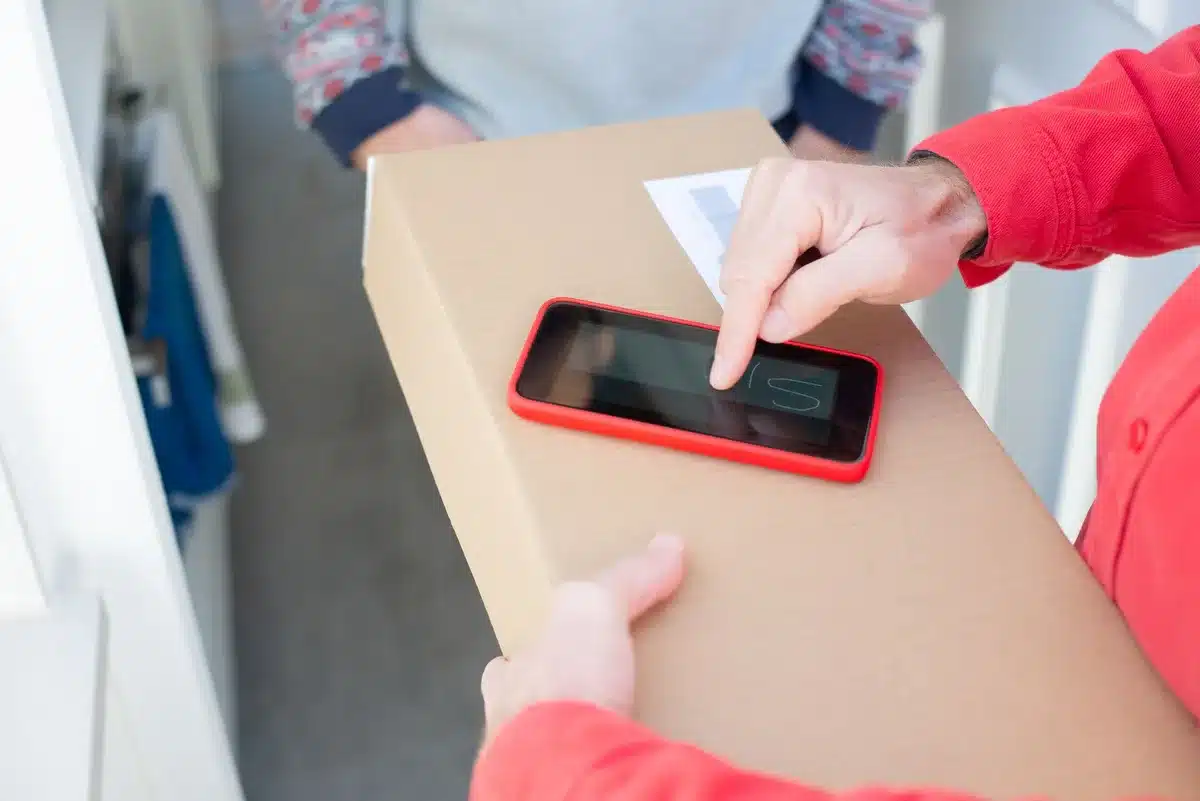An anonymous retail package on a plain table next to an unbranded smartphone box and a small coupon card, neutral studio setting