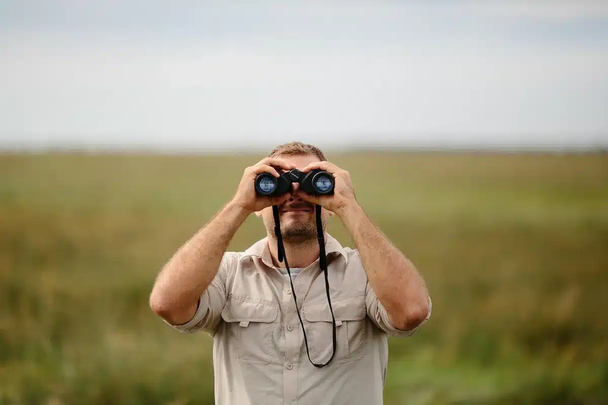 anonymous hiker checking a wrist device with a map-like display on a forest trail, no brand or identifiable person