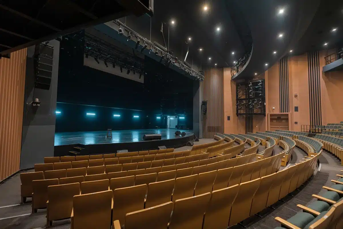 empty conference stage with a single microphone under a spotlight, no people visible, large blank projection screen behind it