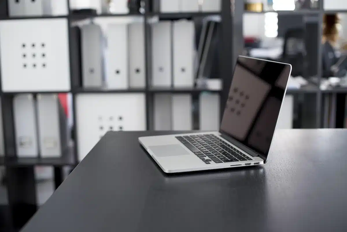 A compact unbranded portable power bank sitting on a wooden desk beside an anonymous smartphone, soft reflections on the metallic surface, no logos visible