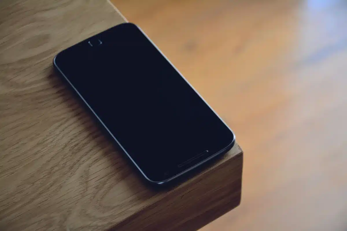 A slim generic smartphone lying on a table beside a USB-C cable and a folded price tag, no logos visible