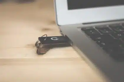 Manos anónimas conectando una memoria USB junto a un portátil con cuadro de formato en pantalla