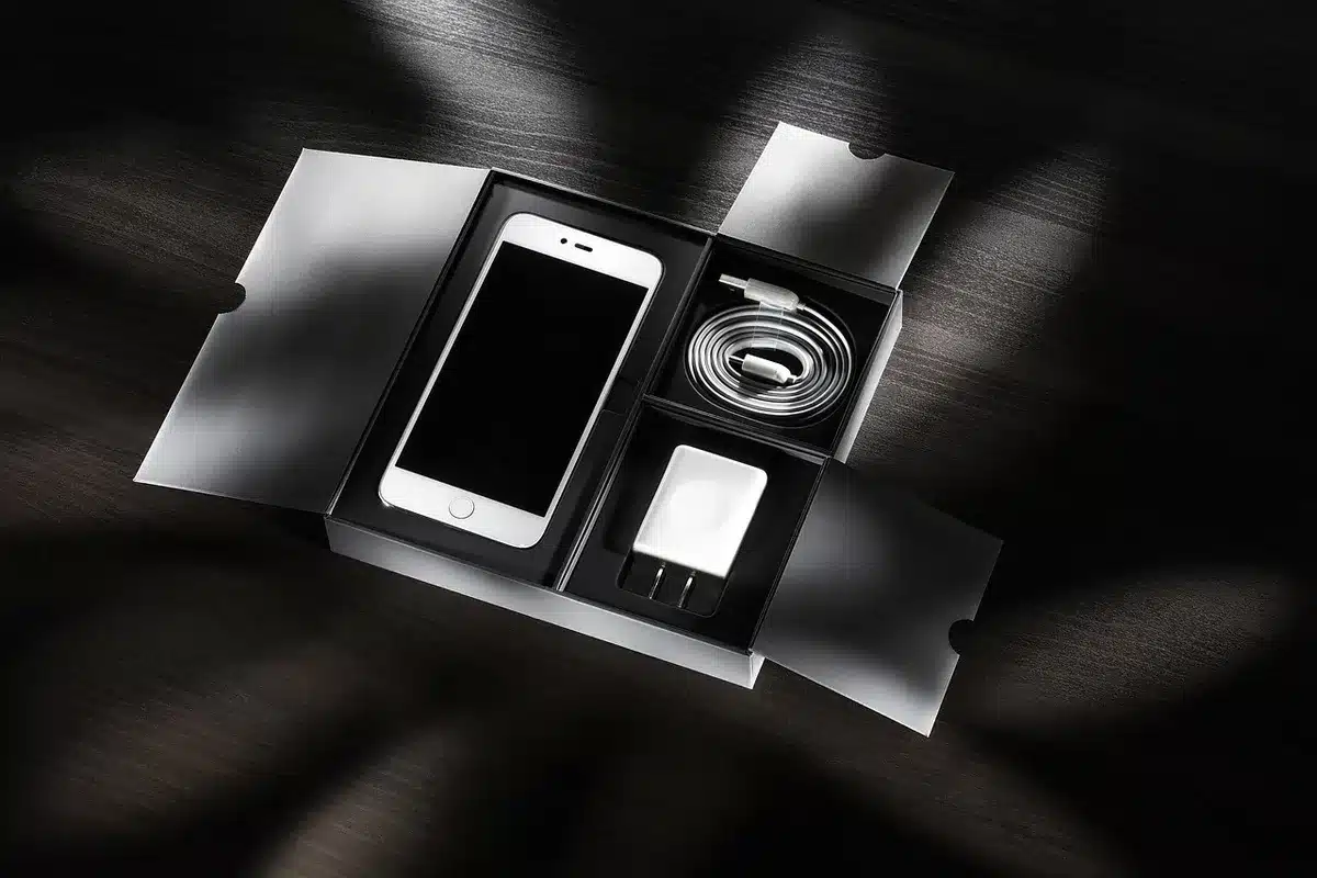 Close-up of an anonymous hand plugging a generic fast charger cable into an unbranded smartphone on a table, battery icon visible but unreadable; no logos